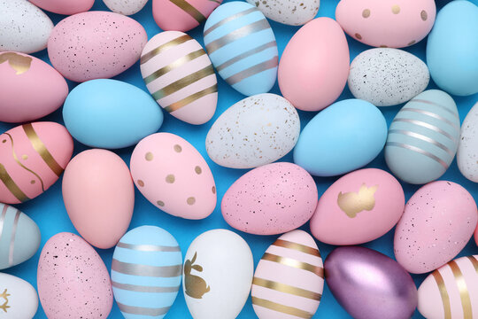Many painted Easter eggs on blue background, flat lay