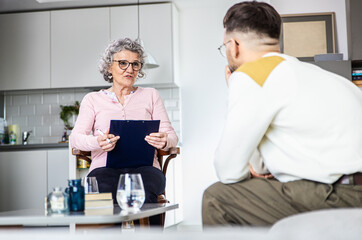 Senior female psychologist talking to man during therapy.