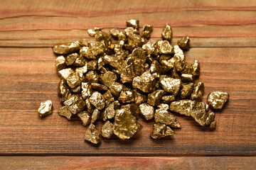 Pile of shiny gold nuggets on wooden table, flat lay