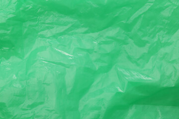 Crumpled green plastic bag as background, top view