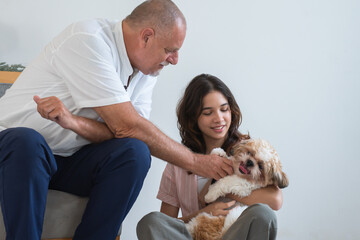 Elderly kind father with his beautiful teenage daughter playing with shih tzu puppy dog at home....