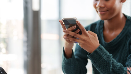 Fototapeta premium Close-up woman using smartphone to send text messages working or playing social media.