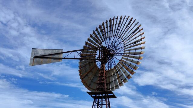 A farm windmill in North Queensland Australia against cloudy blue sky