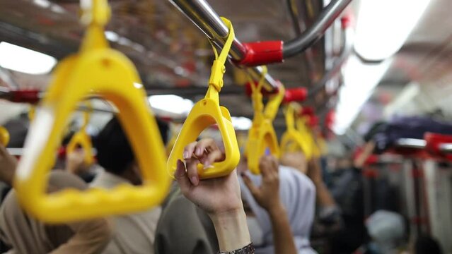 Close-up of Hands holding handrail or grip straps in metro train