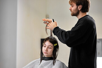 Fototapeta premium Professional male hairdresser cutting female hair in salon