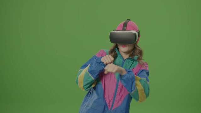 Green Screen. Girl of '80-'90s Style Wearing Virtual Reality Headset Gestures in Augmented Reality. VR Transformation. Concept of Cyberspace of the Fifth Dimension, Digital Worlds, Virtual Adventure - Powered by Adobe