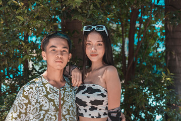 A young and attractive teenage couple at a resort, with foliage as backdrop.