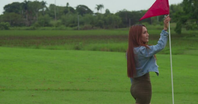 Hispanic girl walking around a flag pole on a golf course