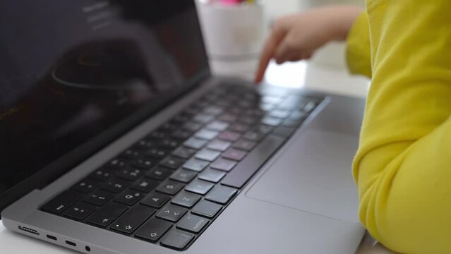 Cute smart caucasian primary School Child typing on the keyboard laptop. Online tutor teaching digital class, web lesson programming on computer at home. Virtual education. Schoolboy girl studying