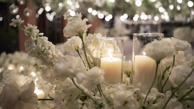Lighted candles and festive arrangement on wedding dinner table
