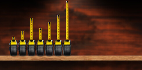 Group of seven tape measures forming a bar graph, on a wooden shelf with copy space, home interior.