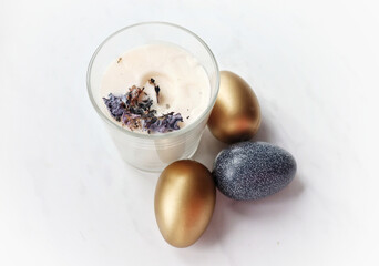 Candle and easter eggs on white table