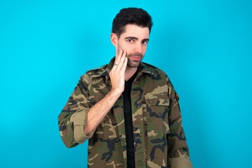 Photo of Young man standing over blue studio background enjoy fresh perfect smooth skin touch face