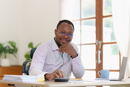 Smiling American African makes financial report and studies annual figures, analyzes profits. Accountant checks status of financial