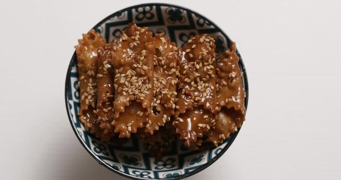 A hand reaches for Chebakia, a sweet Ramadan and Eid al-Fitr treat, symbolizing festive joy and cultural tradition