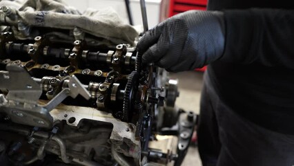 Professional car mechanic with gloves disassembling engine motor from a modern auto in a vehicle repair shop