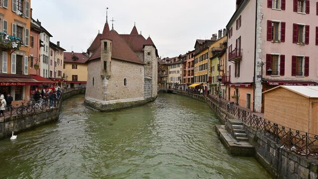 Annecy,France.January 2023.Enchanting glimpse of the historic center with the ancient prison in the middle of the water.The houses with colorful facades overlook the canal. People walk along the canal