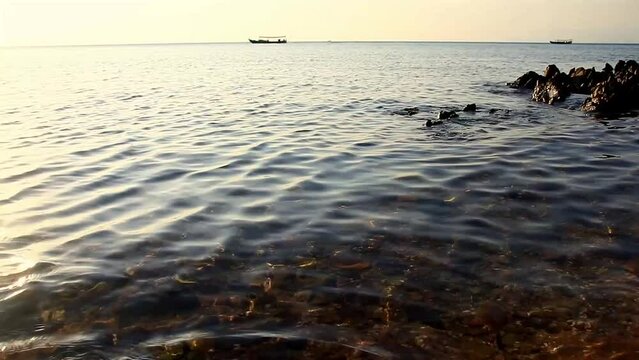 Wide view of a boat sailing by in the horizon off the coast of Koh Tonsay or Rabbit Island, a popular summer destination in Cambodia