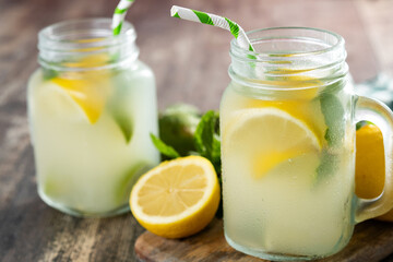 Lemonade drink in a jar glass and ingredients on wooden table.