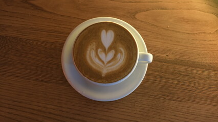 foamy latte with milk on wooden background
