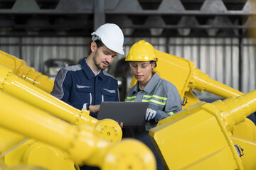 Industrial Manufacturing Robotic Arms Maintaining. Male, female engineer discuss, training inspecting quality parts of robotics arms for manufacturing lines in robotic assembly plant