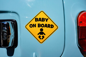 Close up on a yellow sticker in the shape of a warning sign with the inscription 'Baby on Board'...