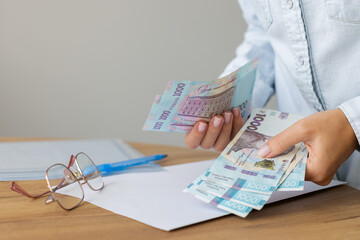 Woman holding Ukrainian 1000 bill banknotes. Count Ukrainian money