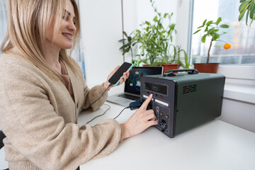 Young woman with portable power station at table in office.
