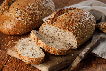 Rustic whole grain bread on a cutting board on a wooden kitchen table