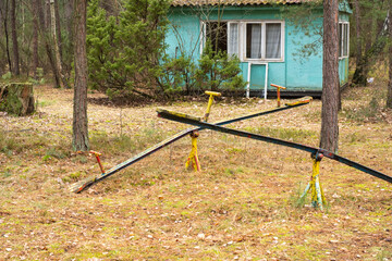 Fototapeta na wymiar An old, dilapidated children's swing in an abandoned and forgotten holiday resort in the forest. Urbex.