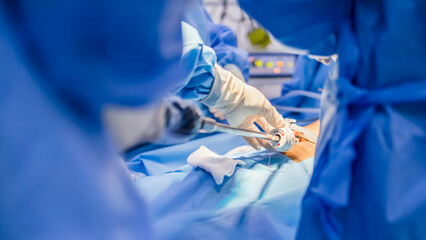Surgeon or doctor in blue gown put medical instrument or device at camera portal during...