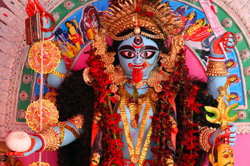 The terrible goddess Kali with her tongue hanging out and a severed head in her hands. Traditional Hindu altar in West Bengal.