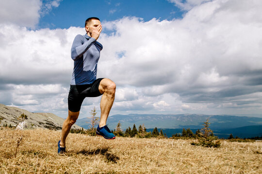 man athlete running on mountain plateau, background blue sky and clouds, sports photo