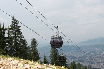 A view of a cabins of the Sarajevo ropeway over the forest in a background of Trebevic mountain