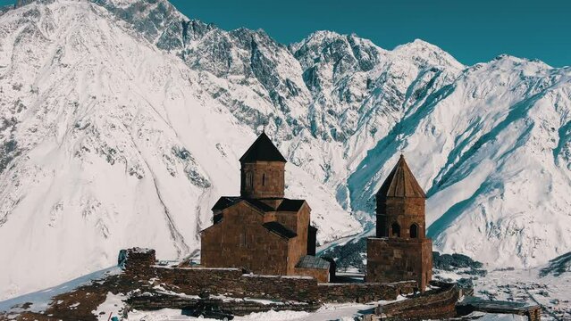 Fantastic aerial view of the ancient Gergeti church against the backdrop of snow-capped mountains in Georgia