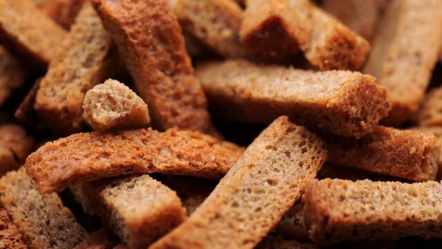 Crispy toasted bread croutons. A pile of hard rusks from dark dry bread close up. Snack for beer. Rye crackers. Snacks rye crackers in a strip. Crouton or brown roasted tostes rotating. 