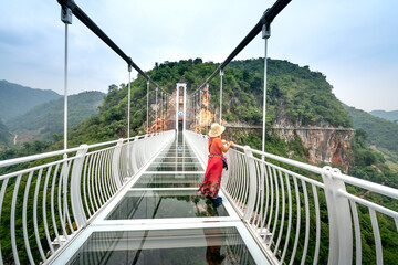 A female tourist enjoys walking on Bach Long Glass Bridge. This is the world's longest pedestrian...