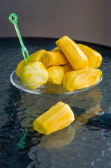 ripe juicy aromatic delicious bright yellow peeled fruits of Indian breadfruit on a glass table