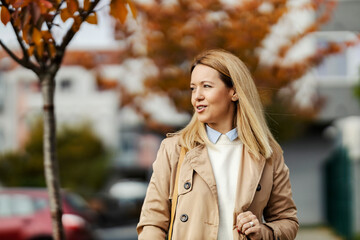 A happy woman is walking in a park at autumn season.