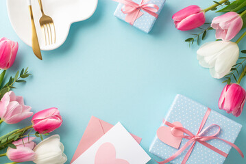 Mother's Day concept. Top view photo of heart shaped plate cutlery white and pink tulips gift boxes with bows and envelope with postal on isolated pastel blue background with copyspace in the middle