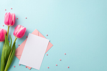 Mother's Day concept. Top view photo of pink envelope paper sheet bunch of tulips and heart shaped sprinkles on isolated pastel blue background with copyspace