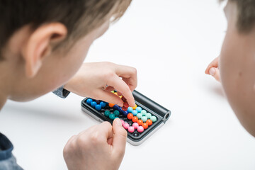 Close up rearview of boys playing educational, strategy board game with black field and colorful balls. Psychotherapy with games for kids. IQ, memory, spatial thinking for kids with disorder