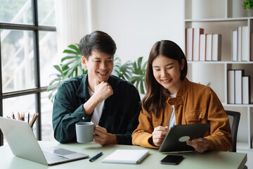 Happy Asian couple lover using laptop together at home in the morning.