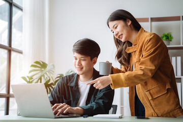 Asian couple looking laptop with happy together in the home. Success of lovers in front of a notebook. Happy couple on social online with a laptop.