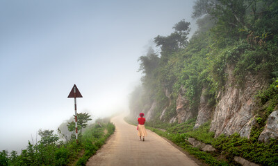 A female tourist feels excited while walking on a foggy forest road in Hang Kia commune, Mai Chau...