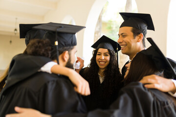 Young women and men hugging celebrating their graduation