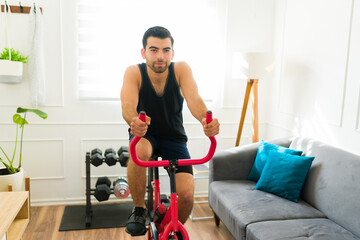 Determined young man doing cardio exercise on a stationary bike