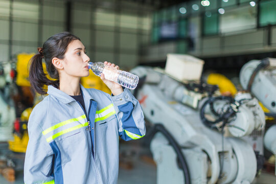 health care woman worker drinking clean water while working in factory machine warehouse for refresh and personal healthy