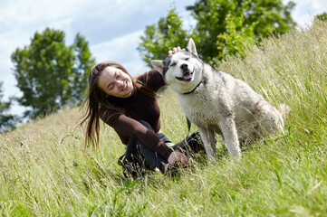 Owner girl playing with her siberian husky at field. Happy smiling woman with dog have a good time...