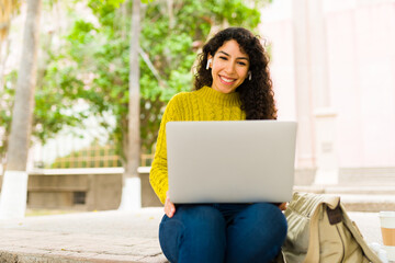 Cheerful woman doing remote work outdoors with a laptop